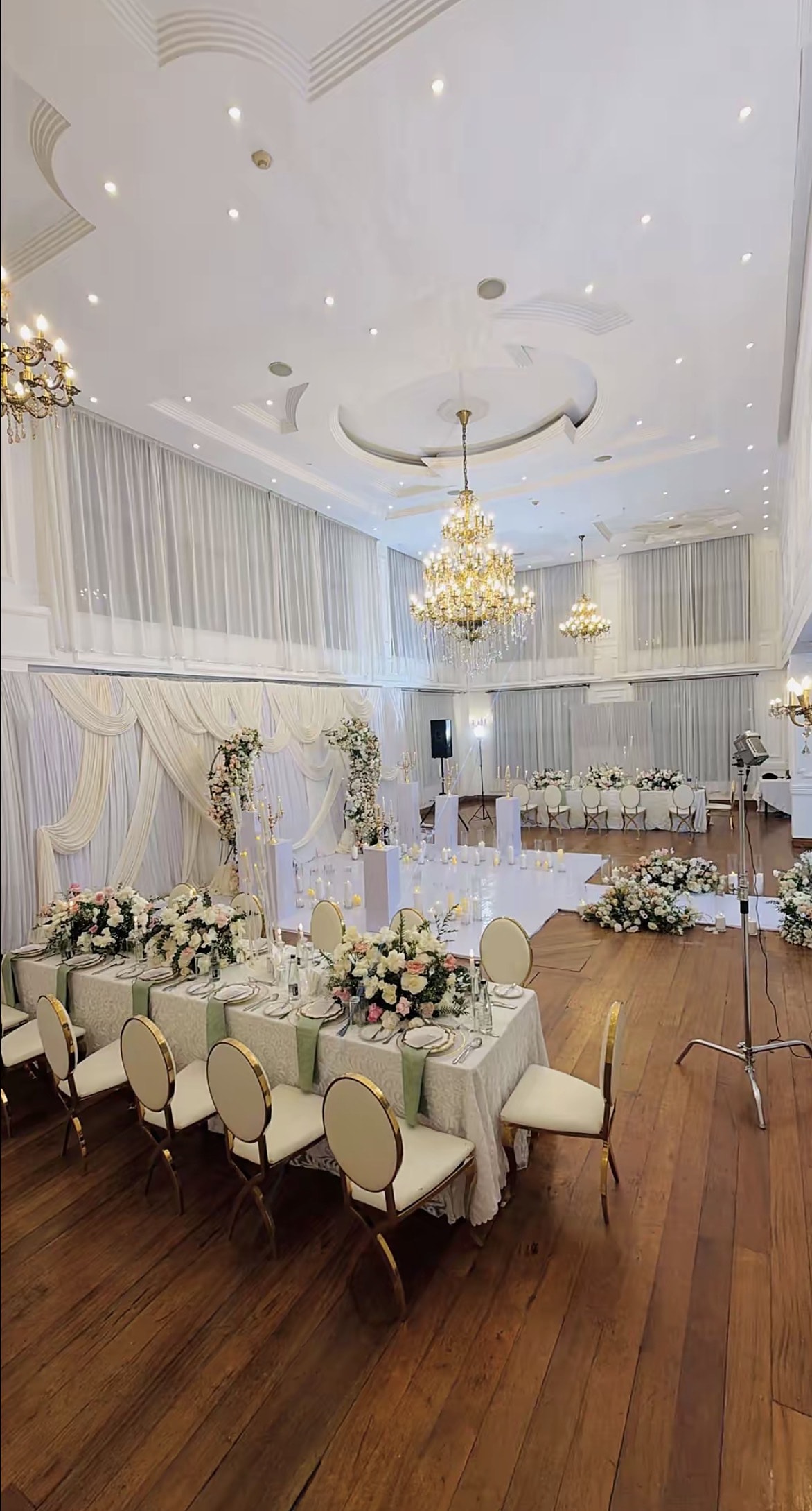 Ballroom with long dining tables, floral centrepieces and chandeliers