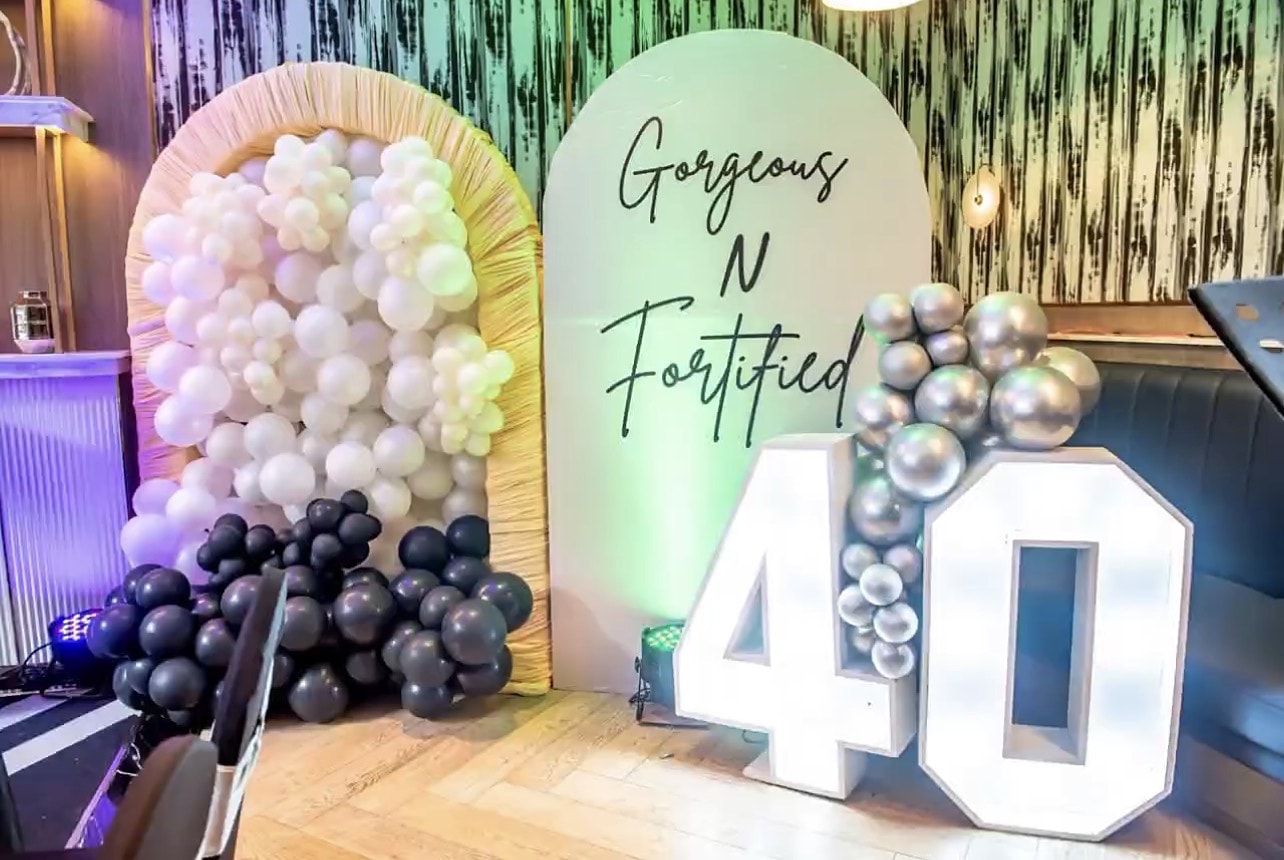 Black, white and silver balloons beside a light-up 40 and a Gorgeous N Fortified sign