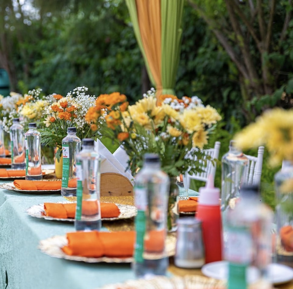 Orange napkins, gold chargers and bright mixed flowers on a garden table
