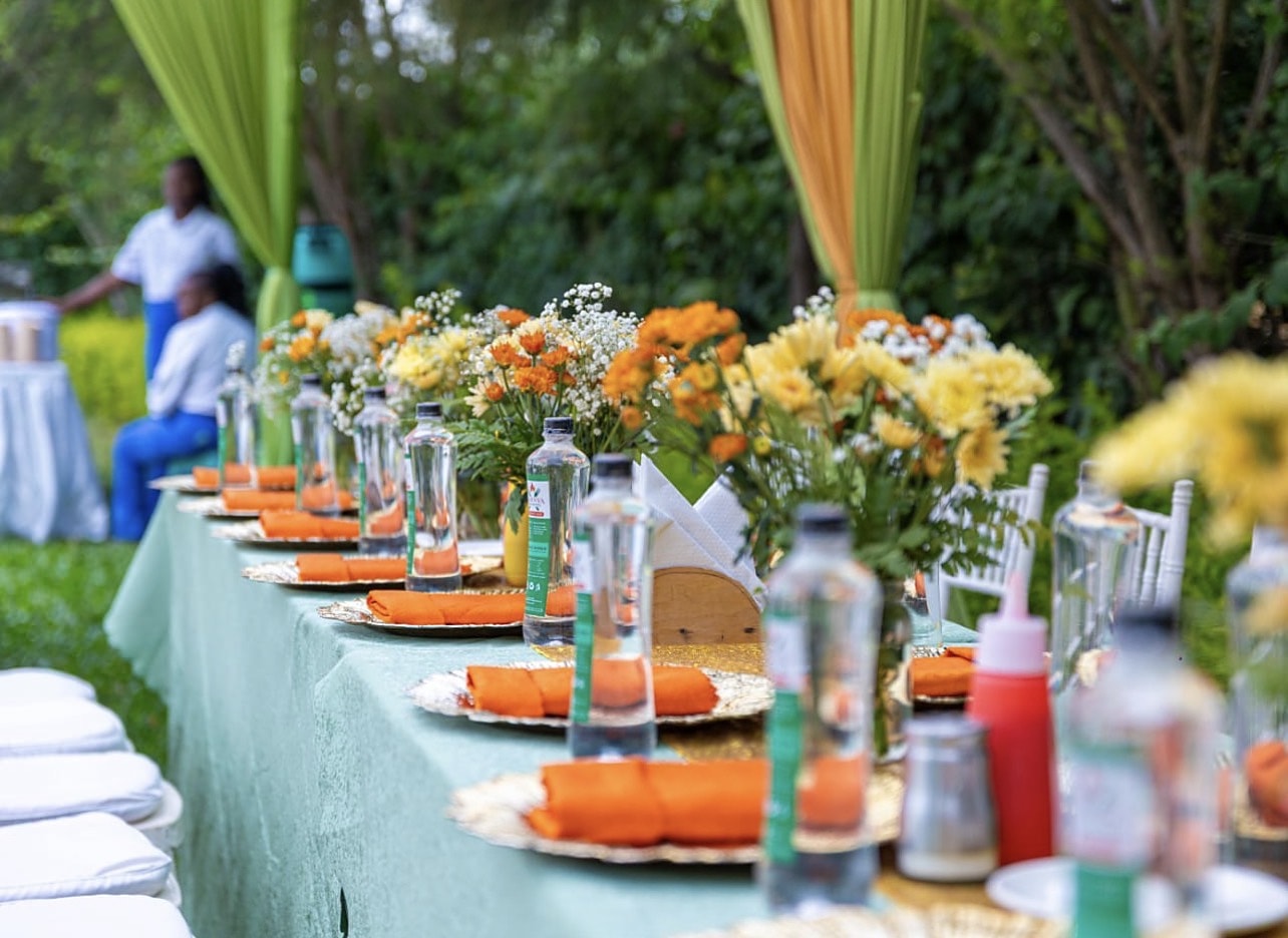 Garden party table with orange napkins and bright floral centrepieces