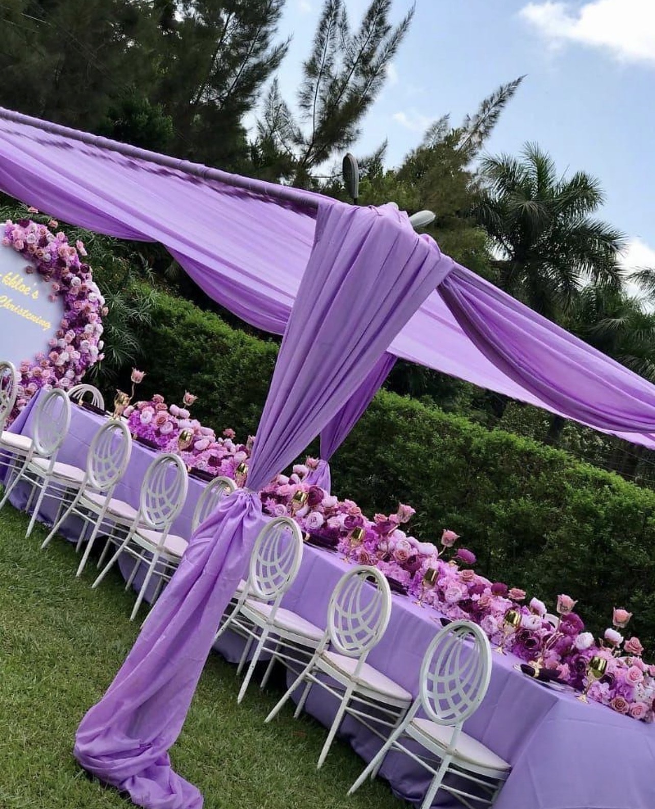 Long garden table under lavender drapery lined with purple and pink flowers
