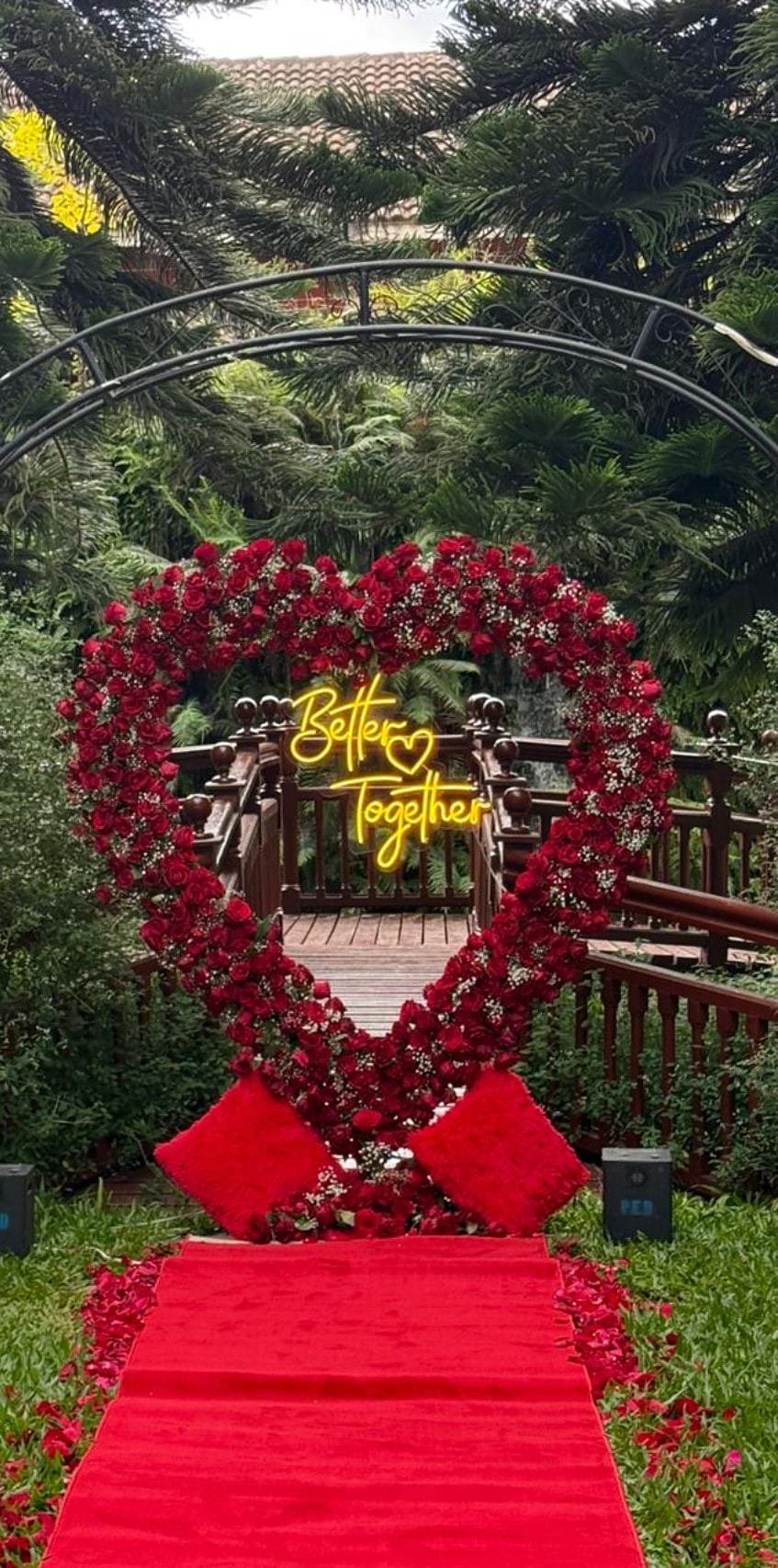 Red rose heart with a Better Together neon and a red carpet in a garden