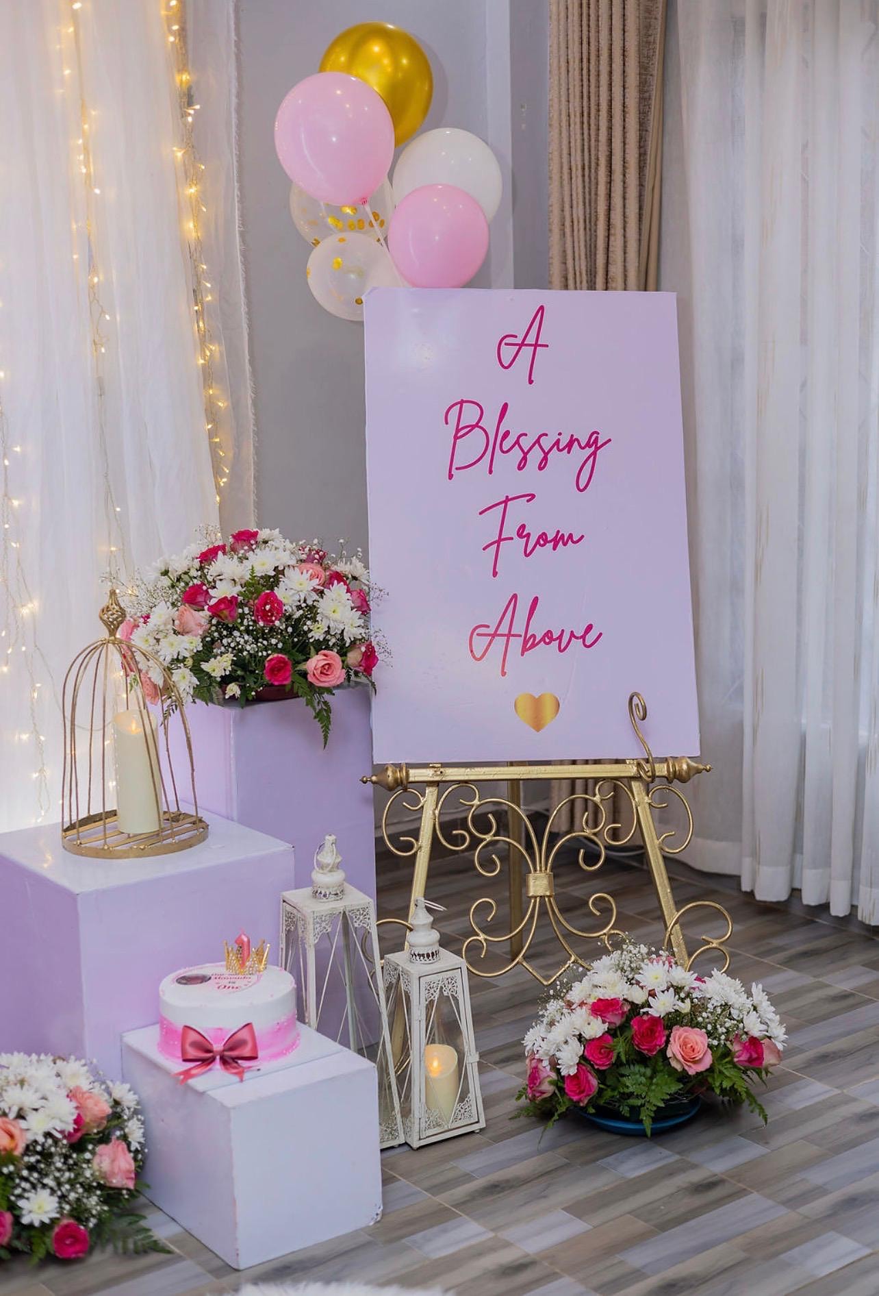 Baby celebration display with a pink sign, cake and roses