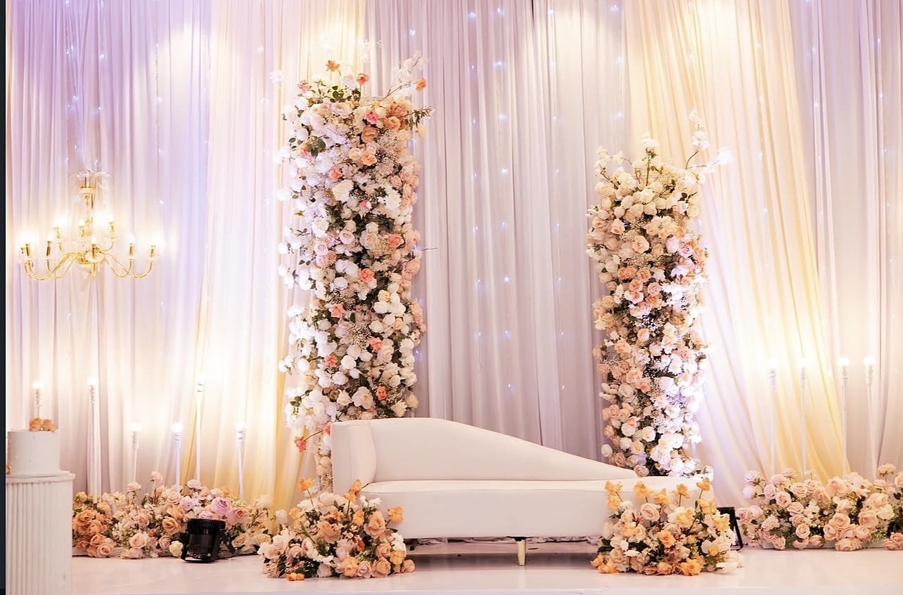 Blush floral columns framing an ivory chaise on a draped stage
