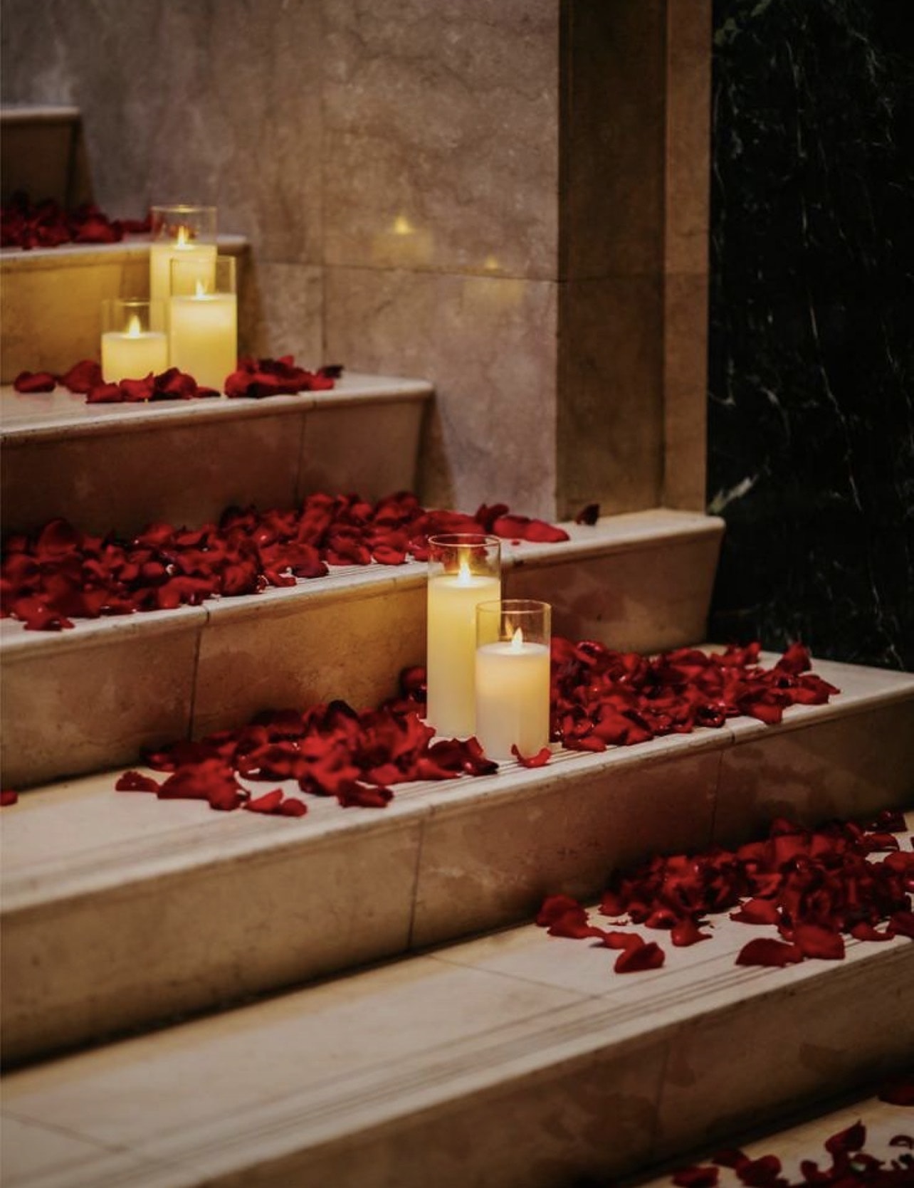 Steps scattered with red rose petals and lit pillar candles