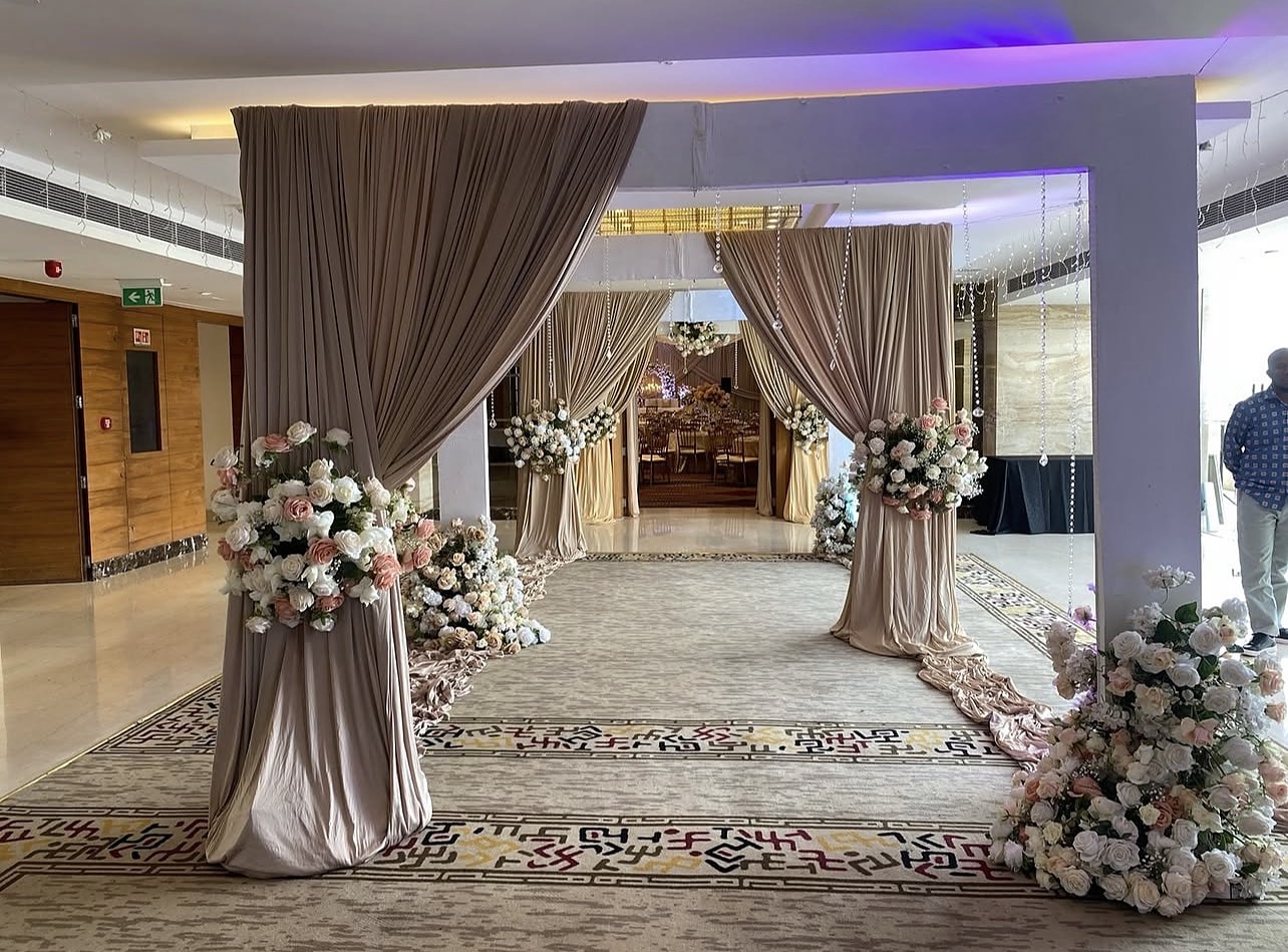 Taupe draped entrance framed with white roses, opening onto a hall