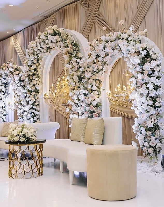 Ivory lounge seating framed by white floral arches