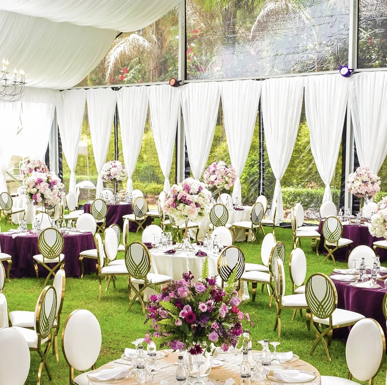 Garden marquee with plum and ivory round tables, gold chairs and pink floral centrepieces