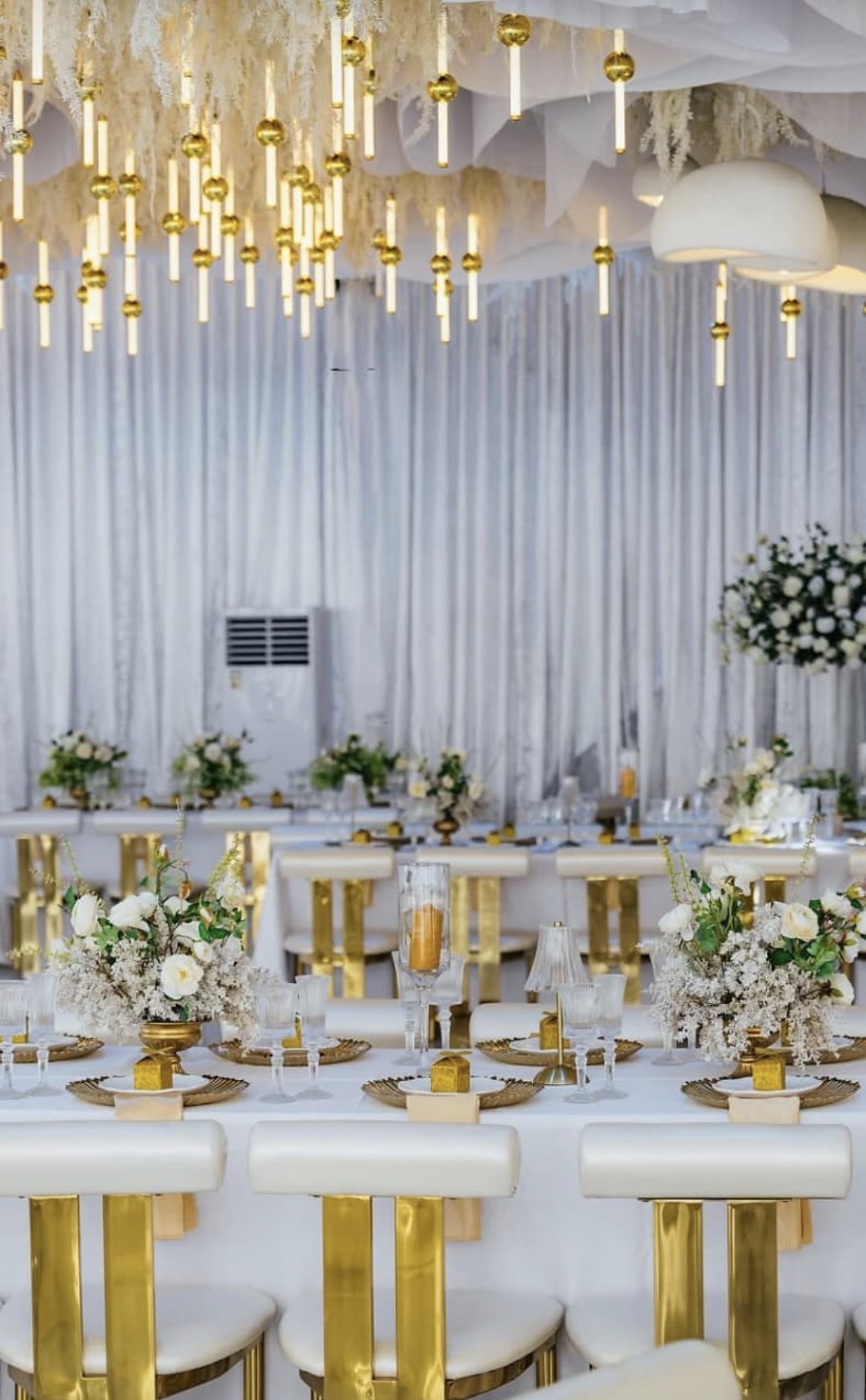 White and gold chairs at a table under suspended candle lights