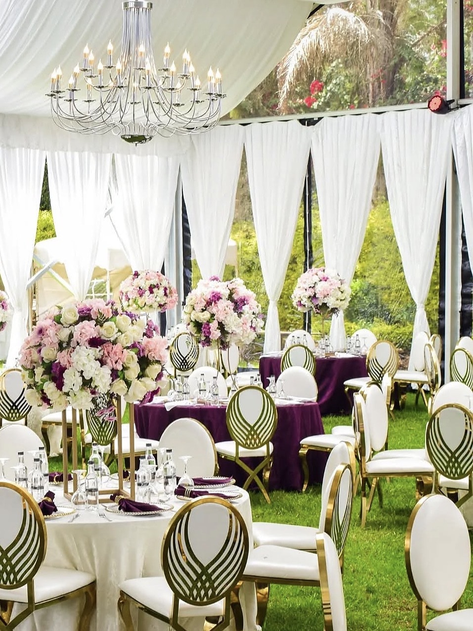 Plum linens and pink rose centrepieces under a draped marquee and chandelier