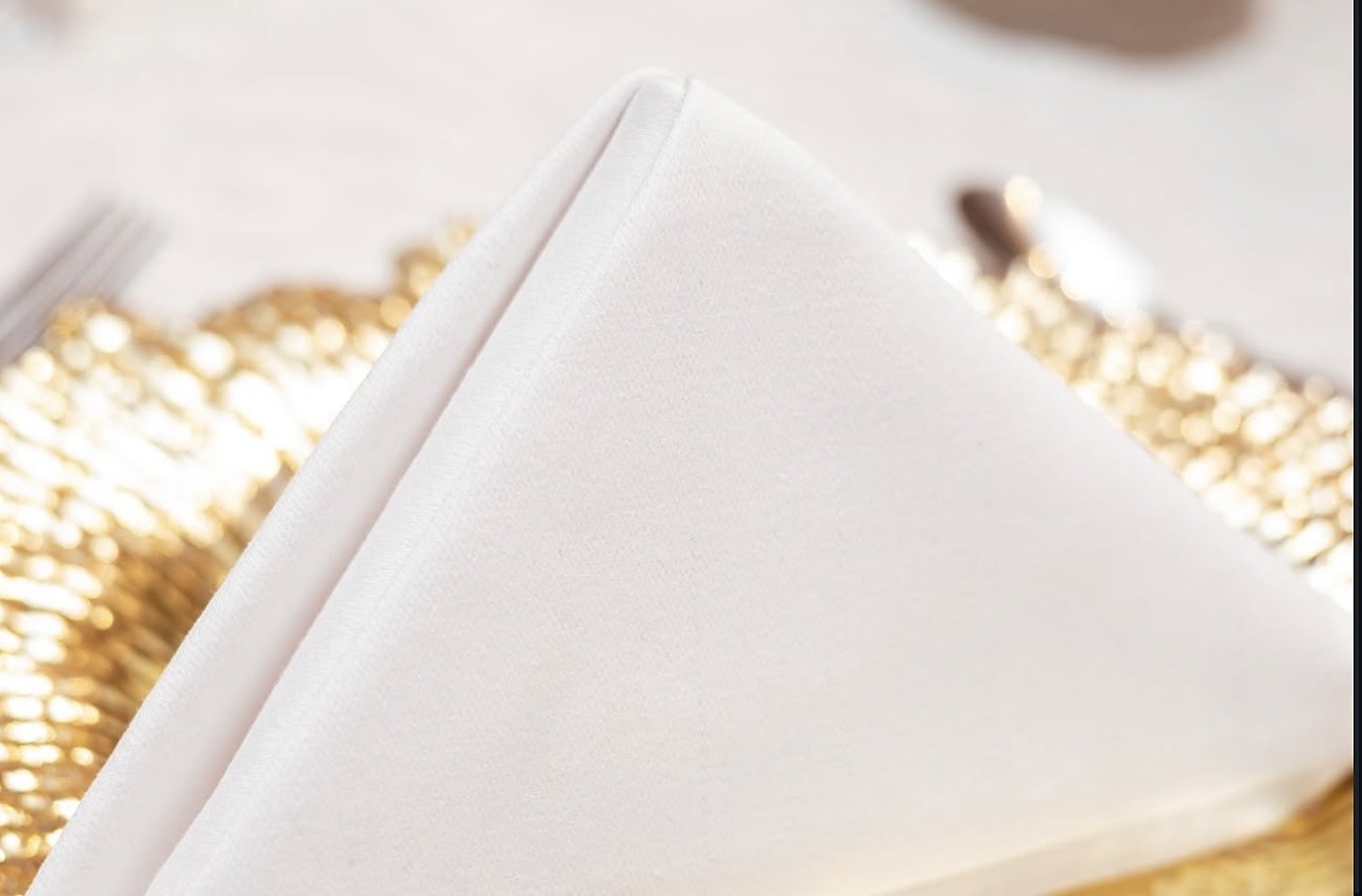 Folded ivory napkin on a gold-beaded charger