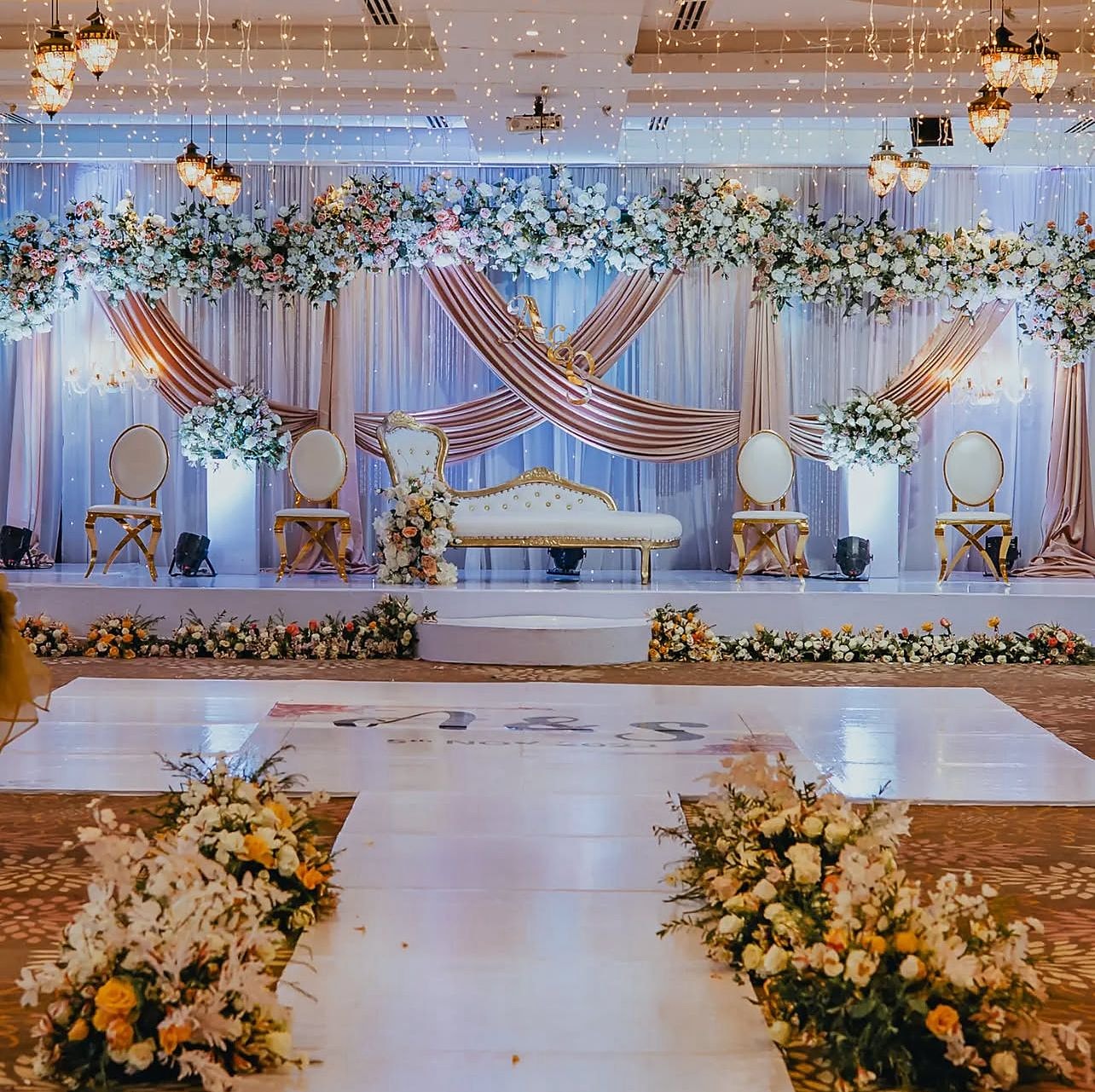 Draped stage with peach and ivory florals above a white dance floor