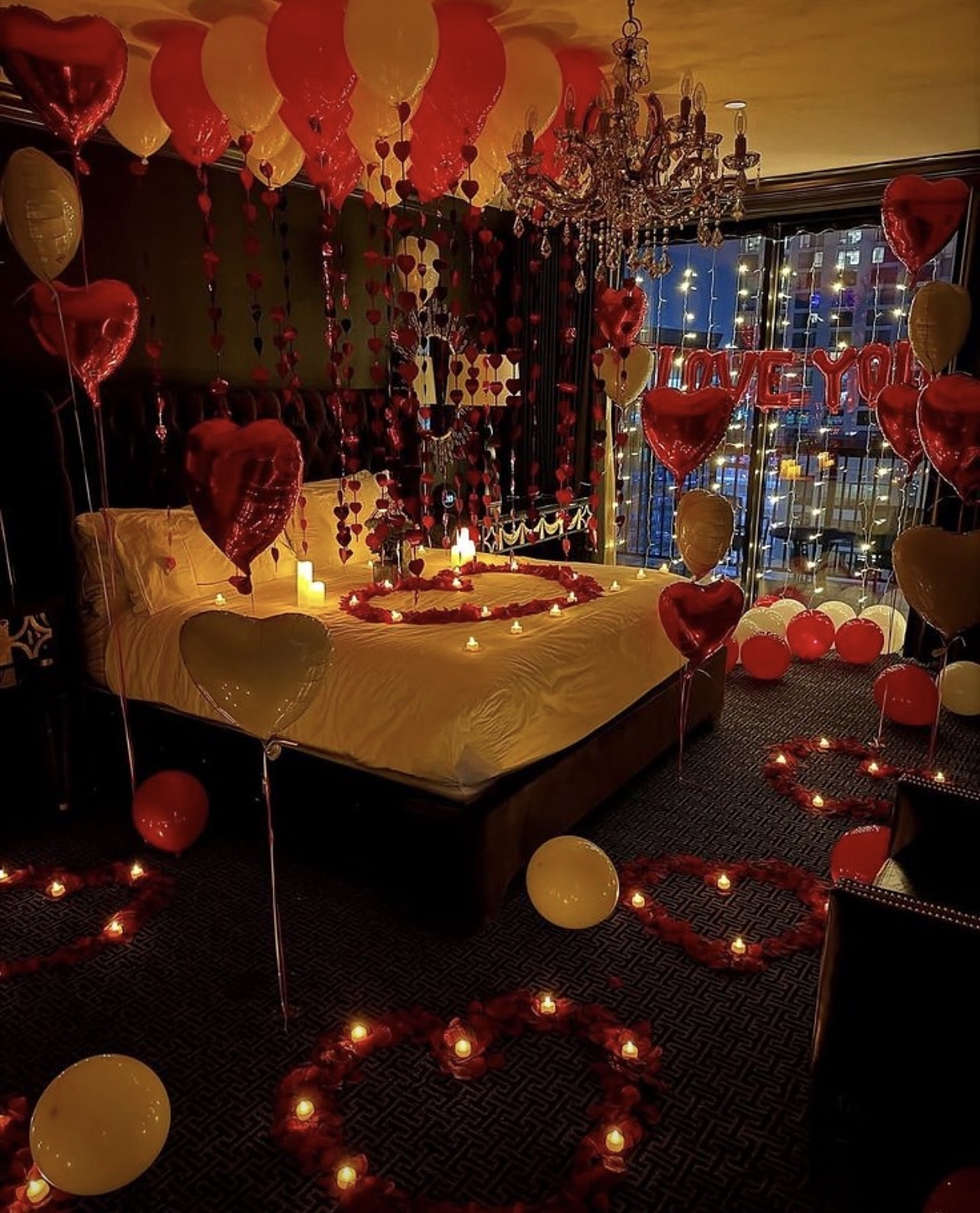 Hotel suite styled for a proposal with red balloons, roses and candles